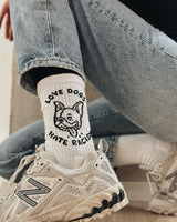 Weiße Sportsocken von NKSP – eingestricktes Hundemotiv mit Schriftzug Love Dogs Hate Racism, getragen zu Sneakern