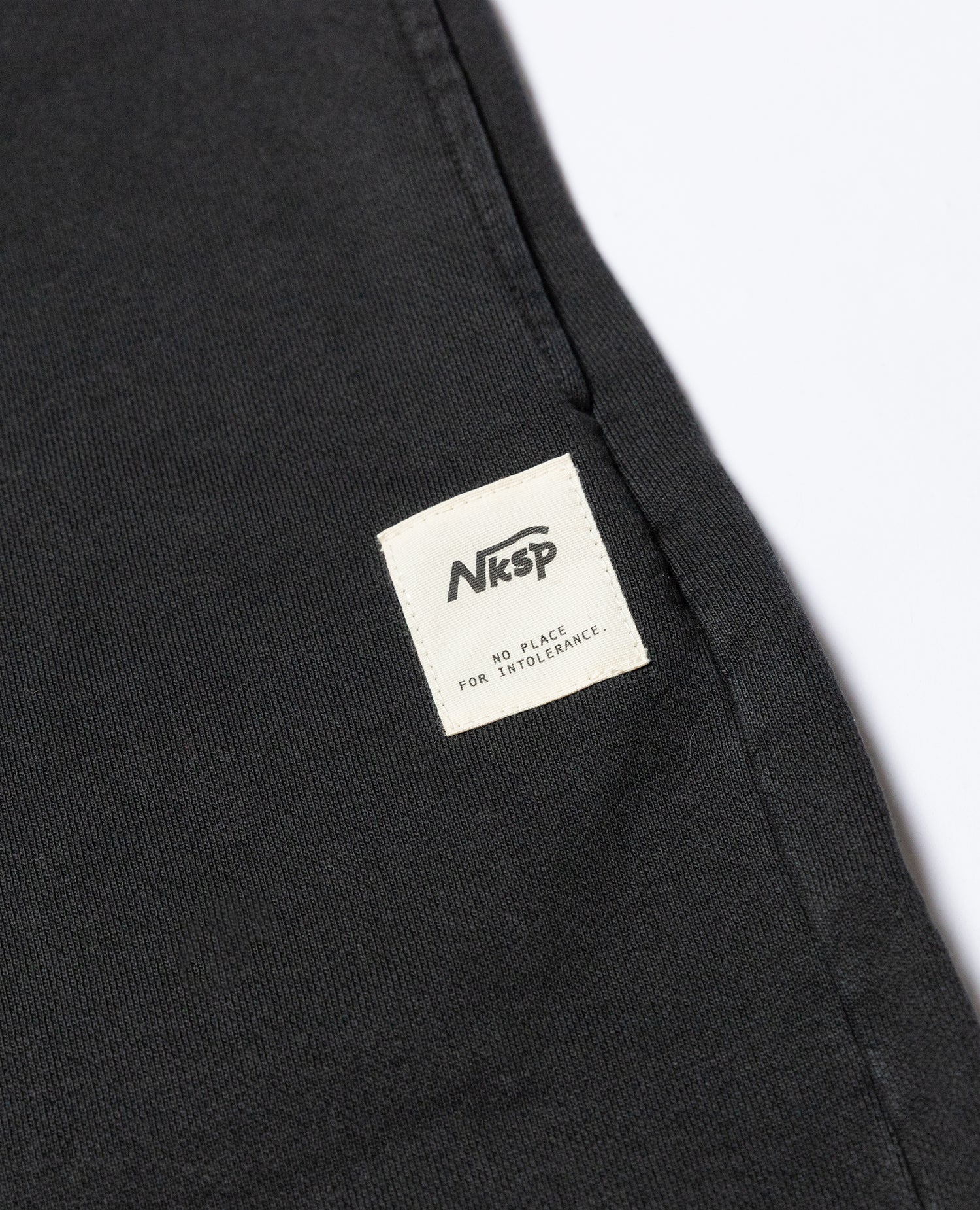 SFW Shorts Schwarz von NKSP – Nahaufnahme des gewebten Nksp-Labels