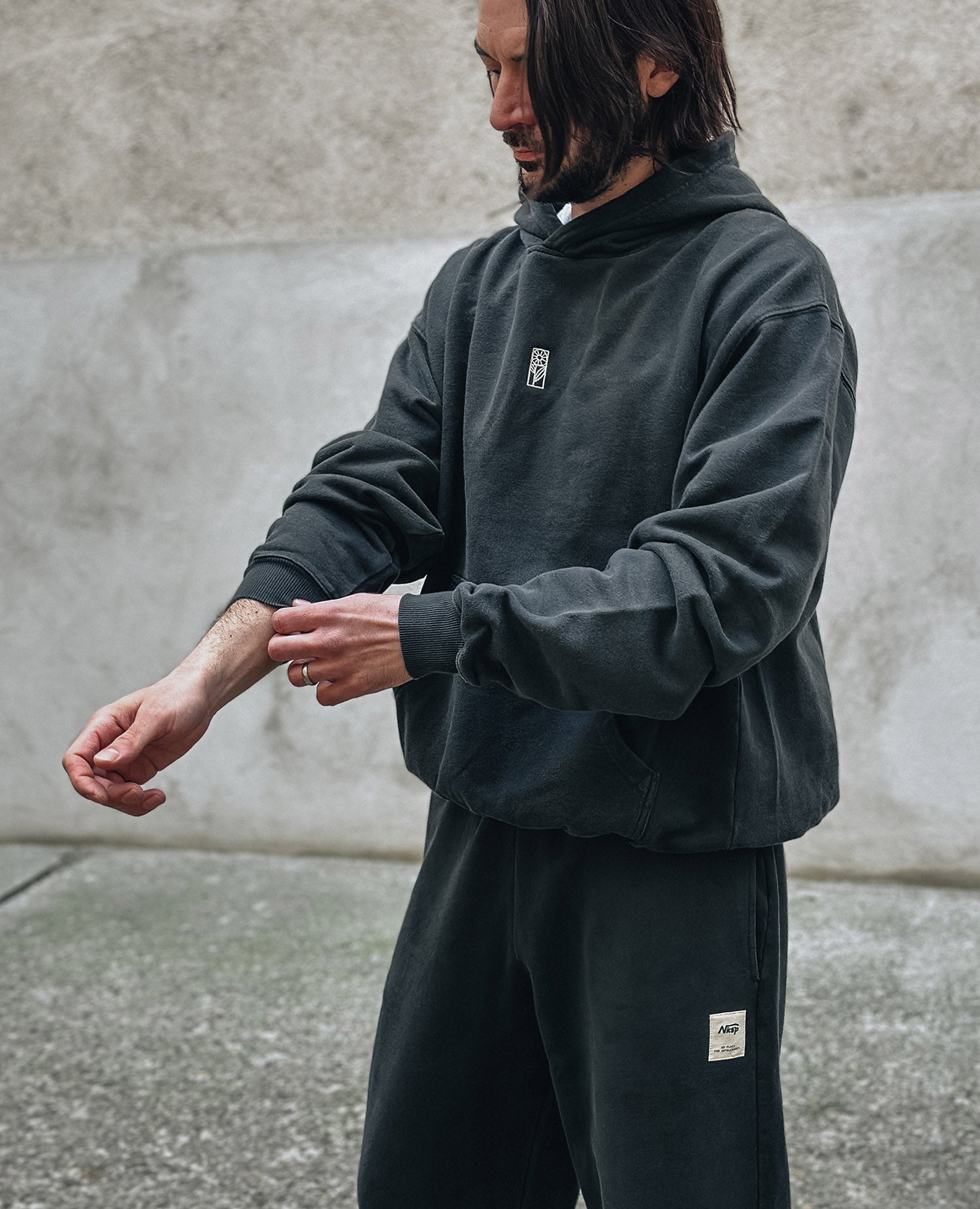 Blume Hoodie Schwarz von NKSP – seitlich am Model, kombiniert mit schwarzen Sweatpants