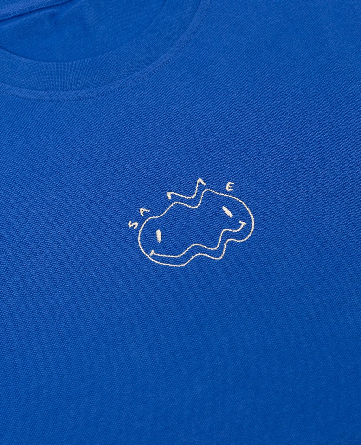 Same Tee Blau von NKSP – Nahaufnahme der weißen Stickerei mit Schriftzug Same